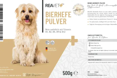 Un chien à poil long et clair, assis, avec un emballage de levure de bière pour chien et chat.