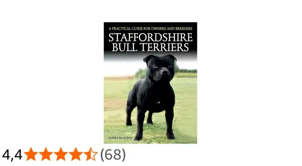 Un Staffordshire Bull Terrier noir, fier et musclé, pose sur l'herbe. La couverture du livre "Staffordshire Bull Terriers" est visible.